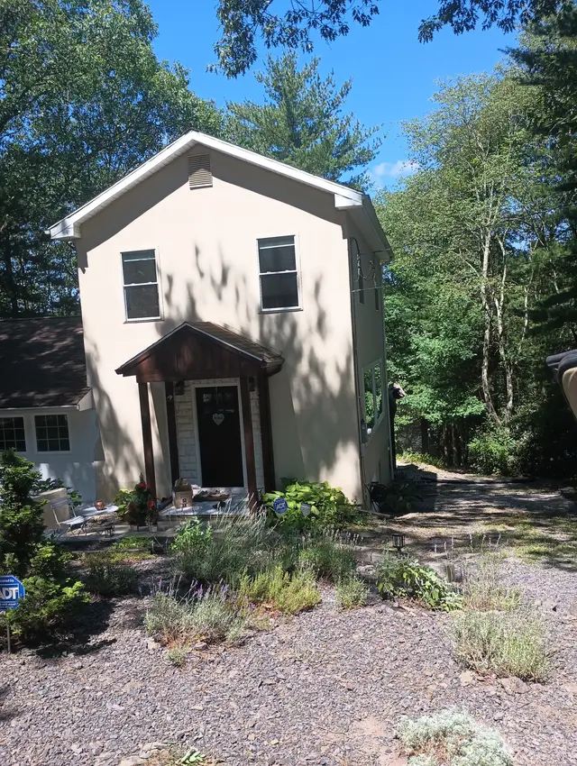 Before: a cream two-story house in the woods with a small gabled porch.